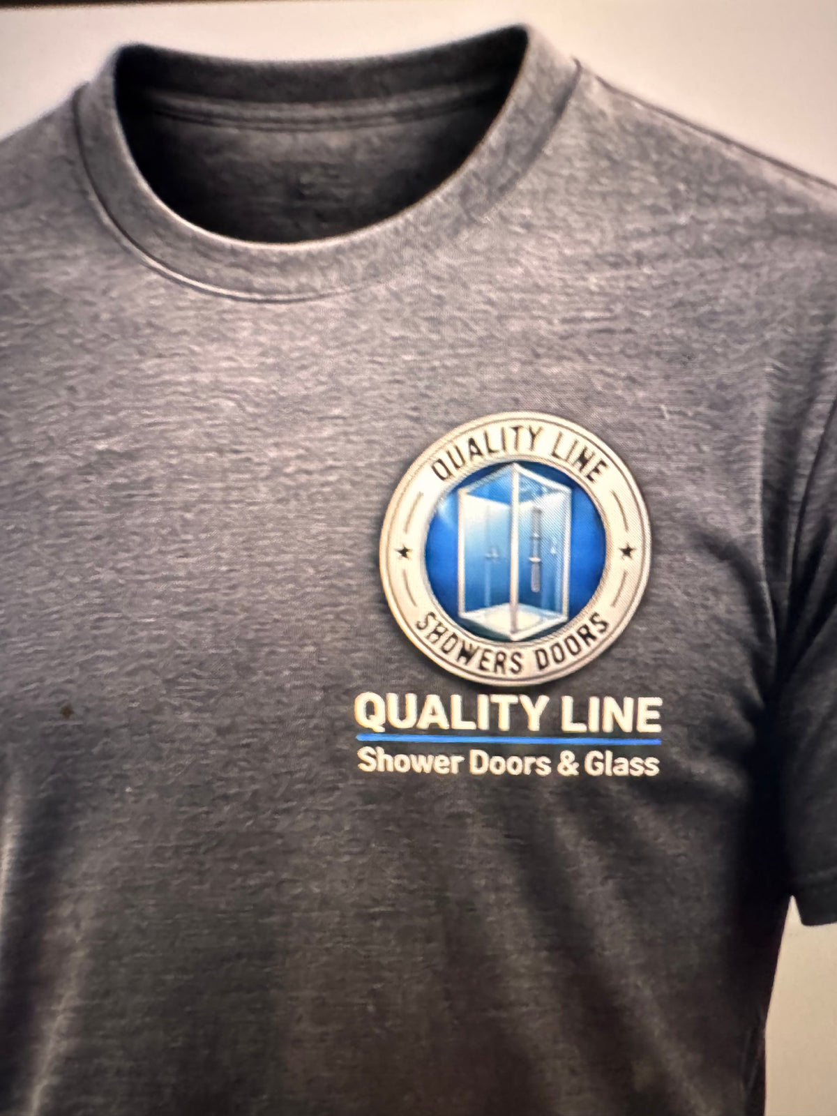 Gray Quality Line uniform with a blue and silver chest logo